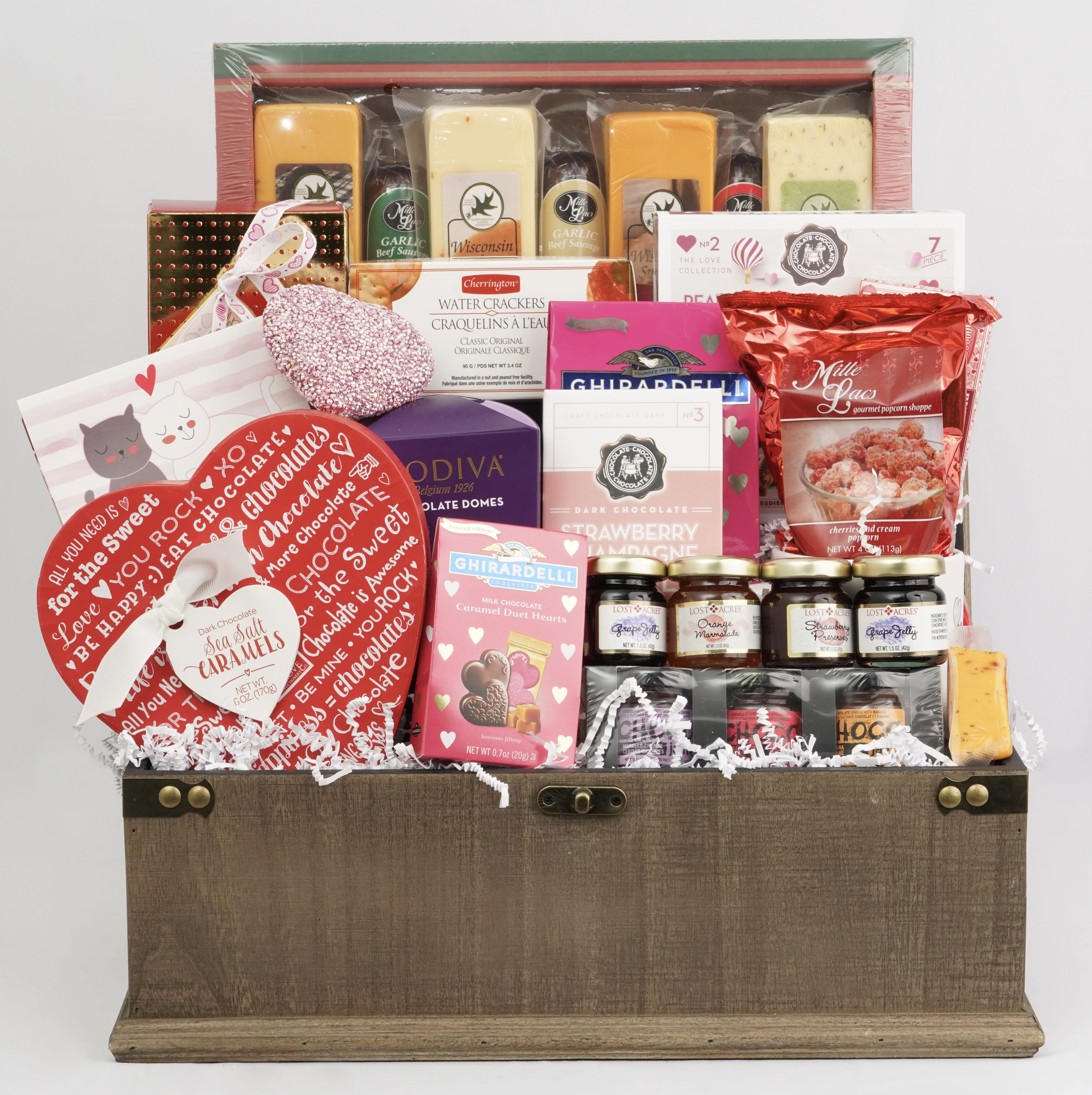 Gift basket filled with chocolates, crackers, jams, and popcorn in a wooden chest
