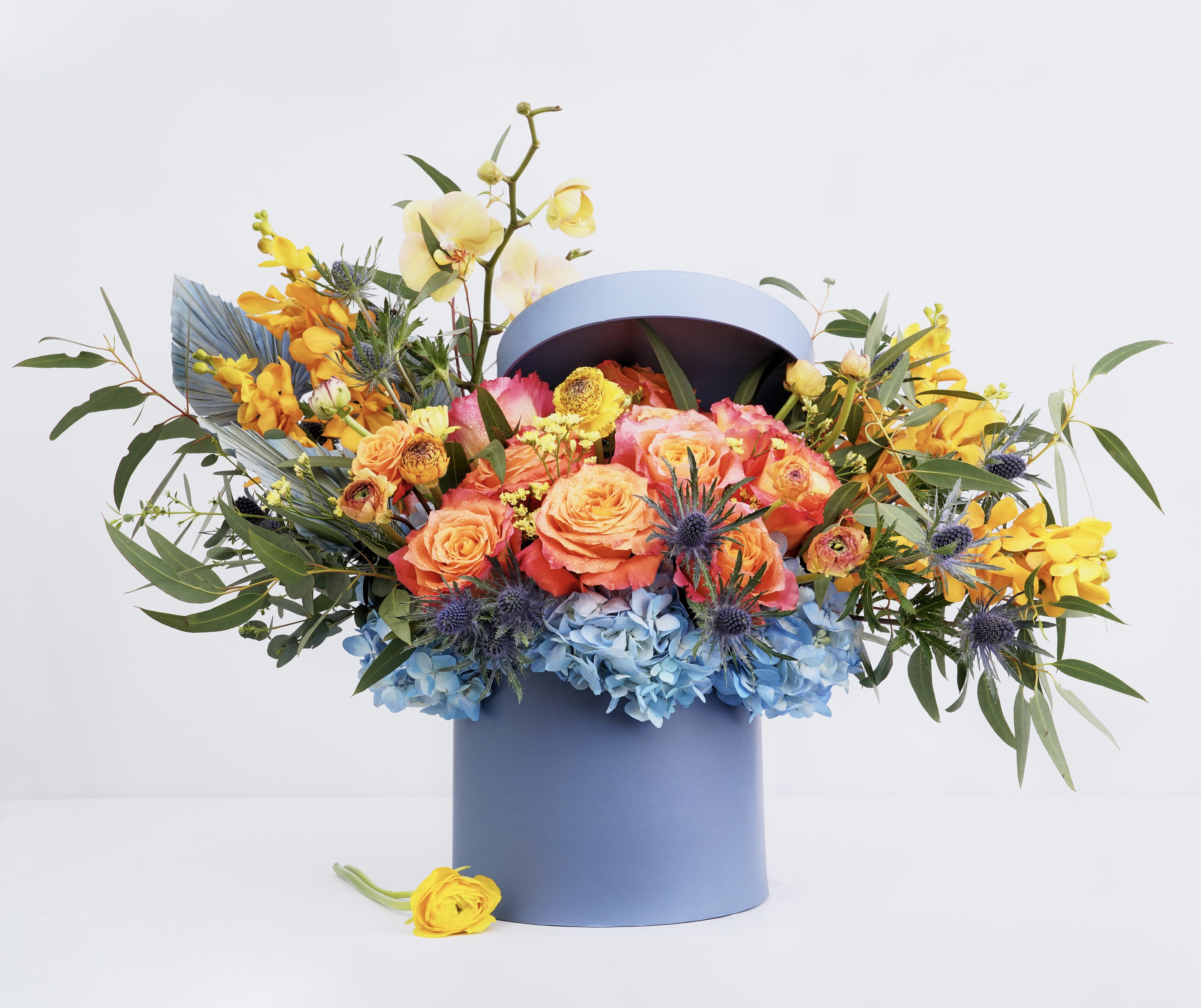 Colorful bouquet in a blue hatbox with roses and orchids