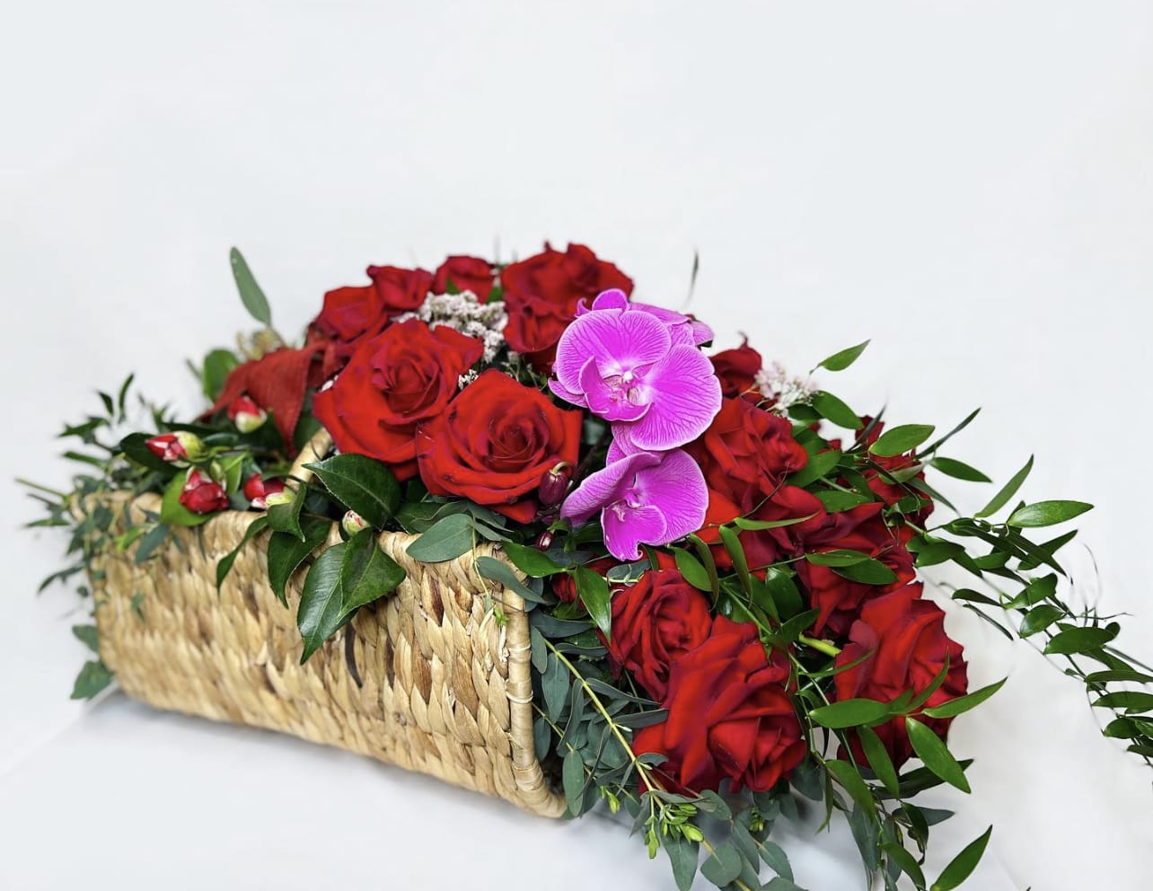 Red roses and pink orchids in a woven basket