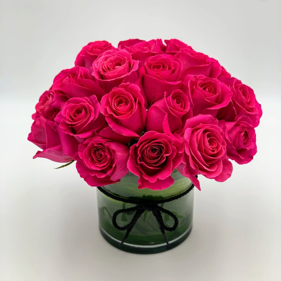 Bouquet of hot pink roses in a green glass vase with a black ribbon