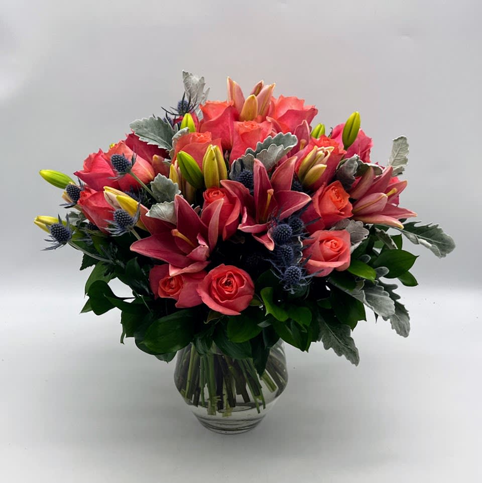 Pink lilies and roses arranged in a clear glass vase