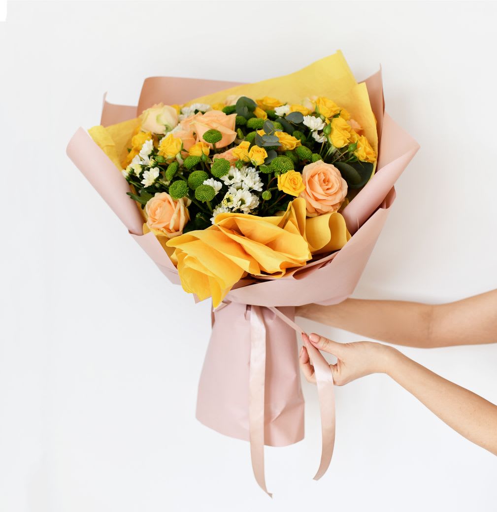 Bouquet of yellow and peach roses wrapped in pink paper