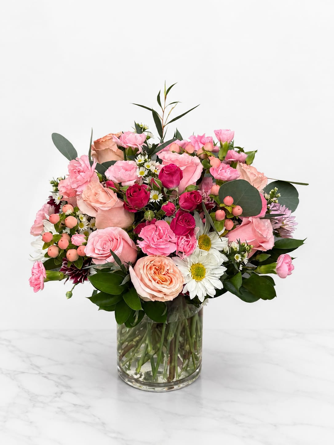 Pink and Soft Bouquet - Soft, romantic, and effortlessly elegant, this blush-toned bouquet is the perfect way to express love, gratitude, or warm wishes. Featuring a graceful mix of pastel pink roses, peach spray roses, lavender mums, delicate alstroemeria, and lush greenery, this arrangement exudes charm and sophistication. Designed in a clear glass cylinder vase, it offers a clean, modern presentation that complements any setting—from home décor to heartfelt gifts. Whether you're celebrating a birthday, anniversary, new baby, or simply want to brighten someone’s day, this bouquet is a beautiful reminder of how much you care. The soft color palette creates a calming and uplifting effect, ideal for sending comfort or joy. Handcrafted with premium, fresh flowers by expert florists, this design is made to impress and delight. Order now for local delivery and let this enchanting floral arrangement speak your emotions with grace and beauty. A timeless gift for any occasion.
