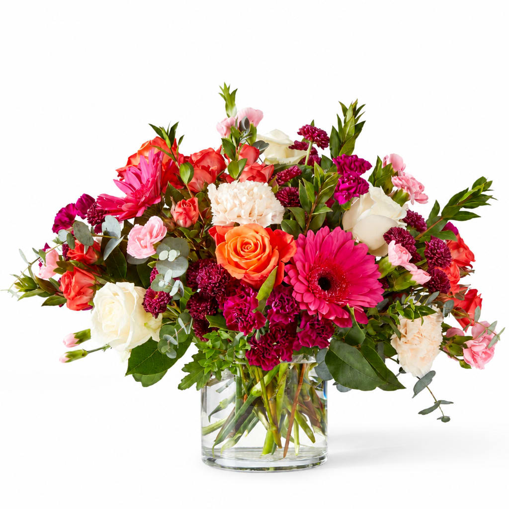 Mixed pink, red, and white flowers in a clear glass vase