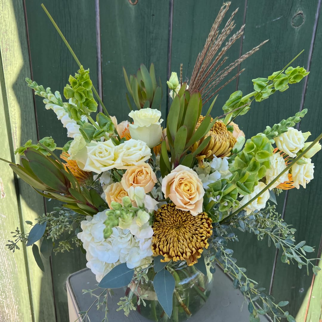 Bouquet of white and peach roses with green foliage in a glass vase