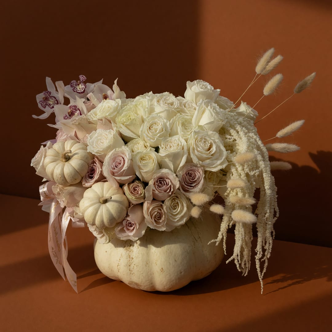 Cream and blush rose arrangement in a white pumpkin vase with dried accents