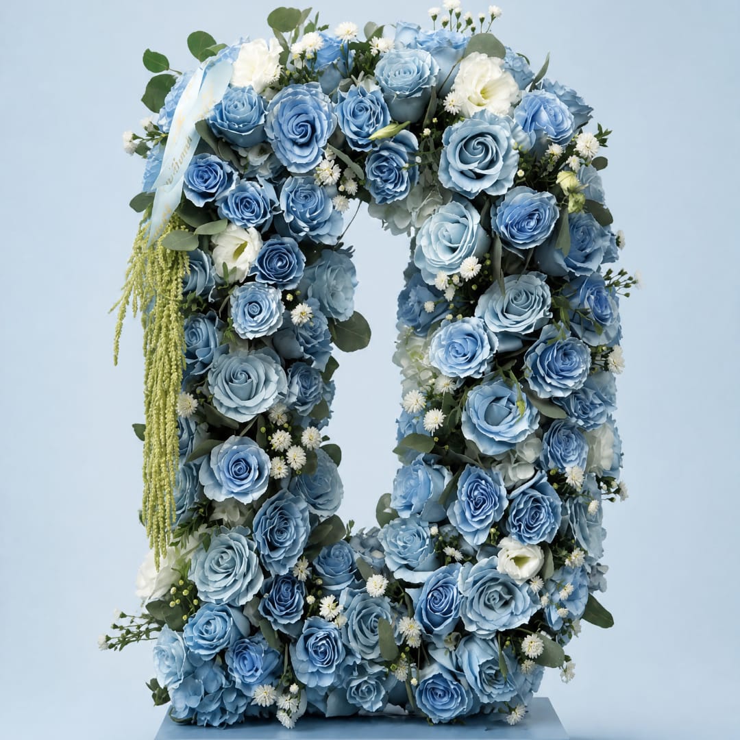 Blue rose floral wreath with white accents and ribbon on a stand