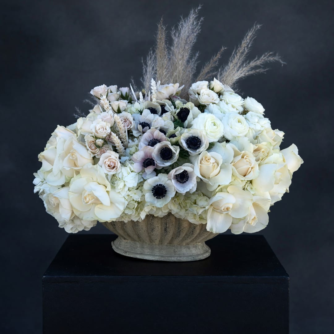 Cream rose and anemone arrangement in a stone urn