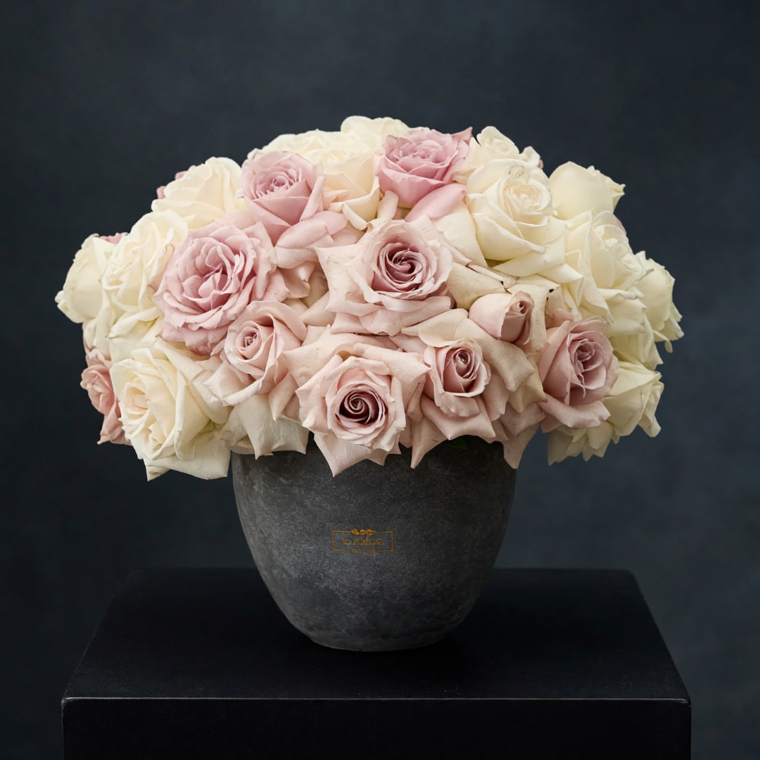 Pink and white roses arranged in a dark vase