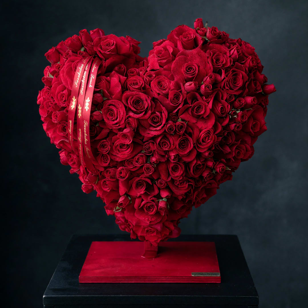 Heart-shaped arrangement of red roses on a red base