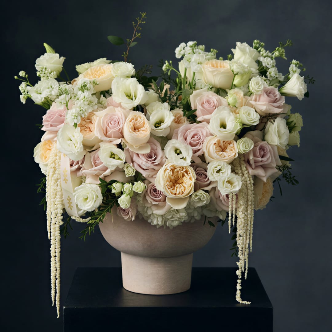 Large pastel floral arrangement in a beige pedestal vase