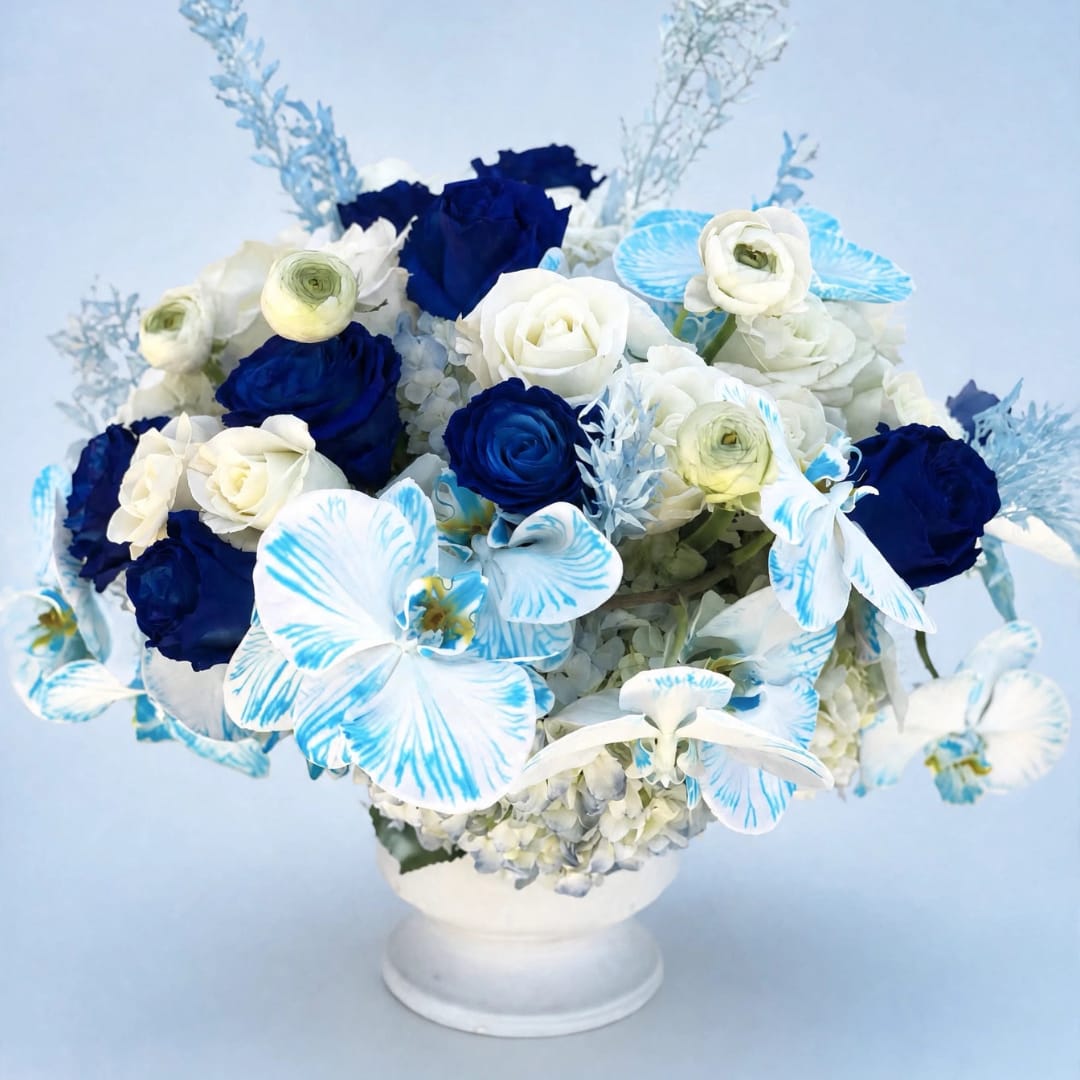 Blue and white floral arrangement in a white pedestal vase