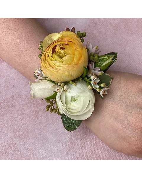 White + Yellow Wrist Corsage - Brighten up your special occasion with this charming white and yellow wrist corsage. Featuring a soft blend of creamy white flowers and a vibrant yellow focal bloom, this piece brings a fresh, cheerful, and elegant touch to any outfit.  