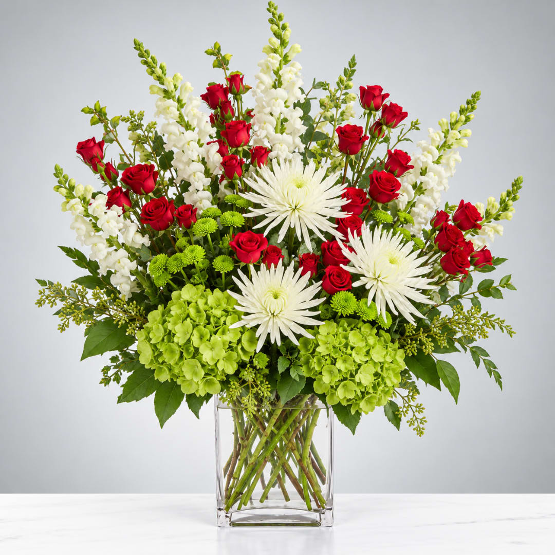 Red roses and white blooms in a clear glass vase with green hydrangeas