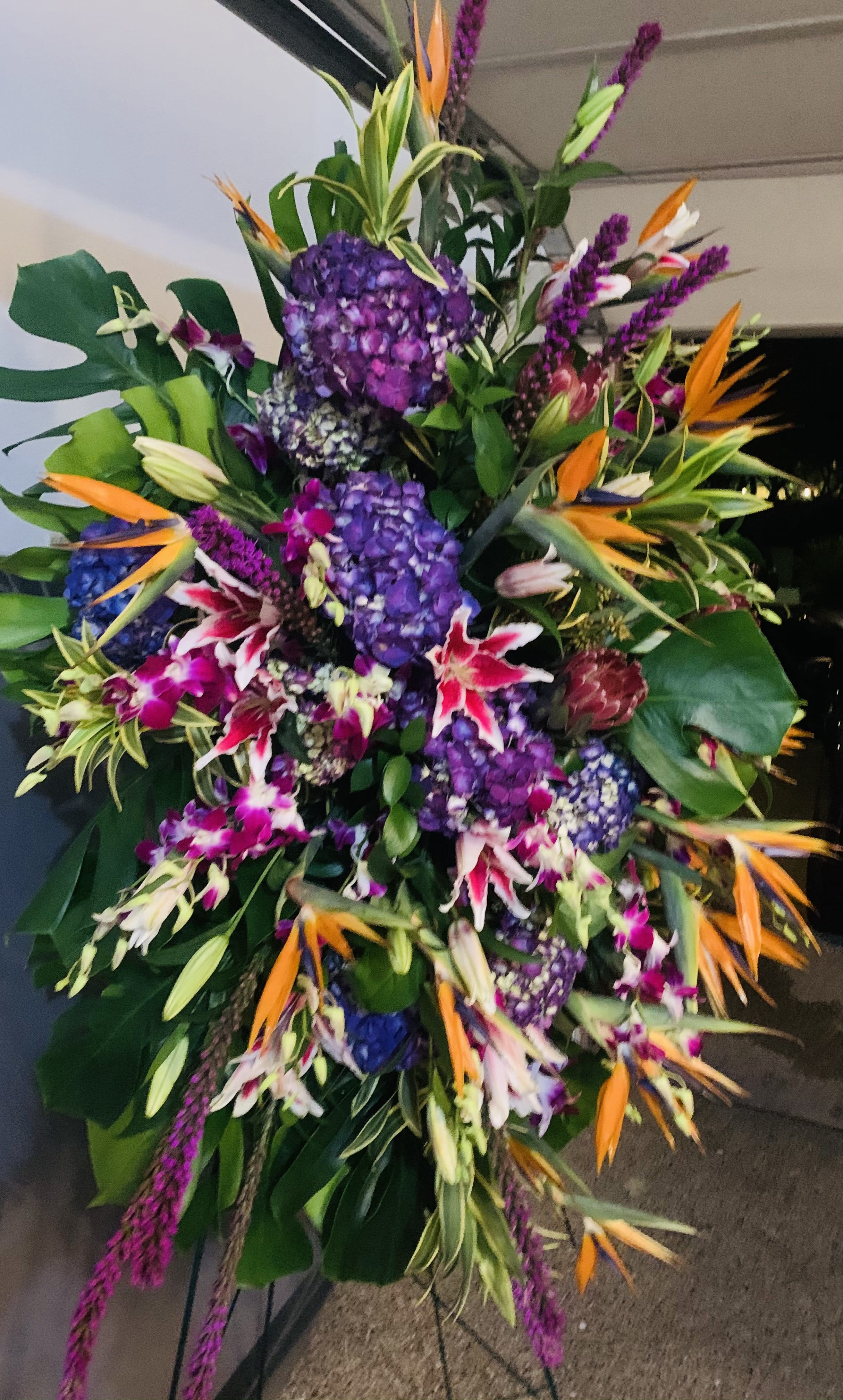 Large tropical floral spray with purple hydrangeas and orange bird-of-paradise blooms
