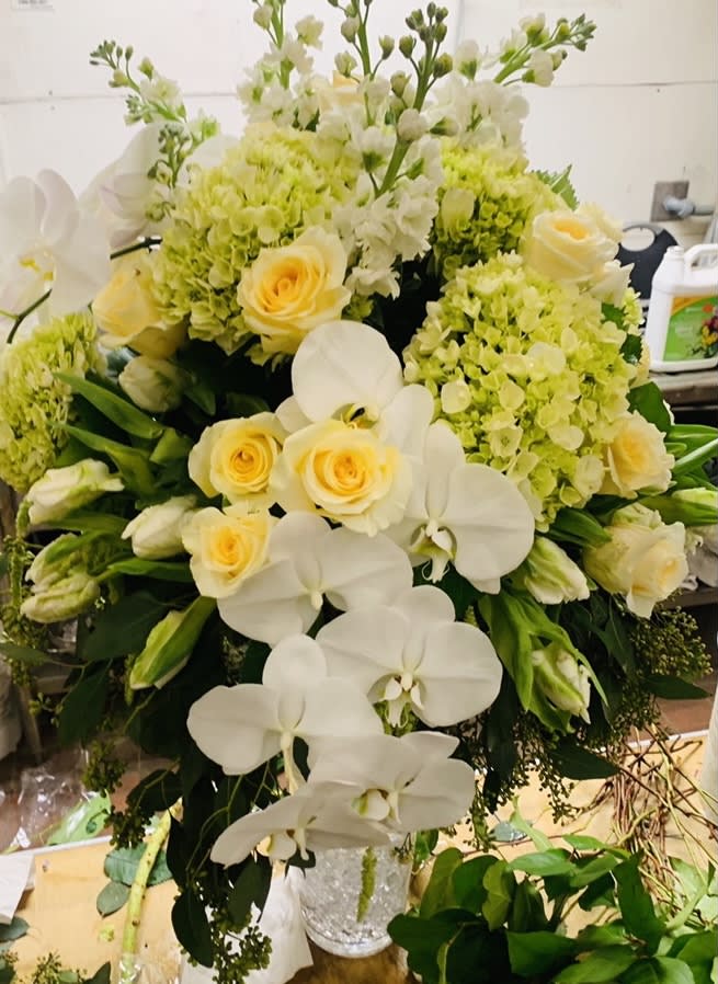 White orchids and pale yellow roses in a silver vase