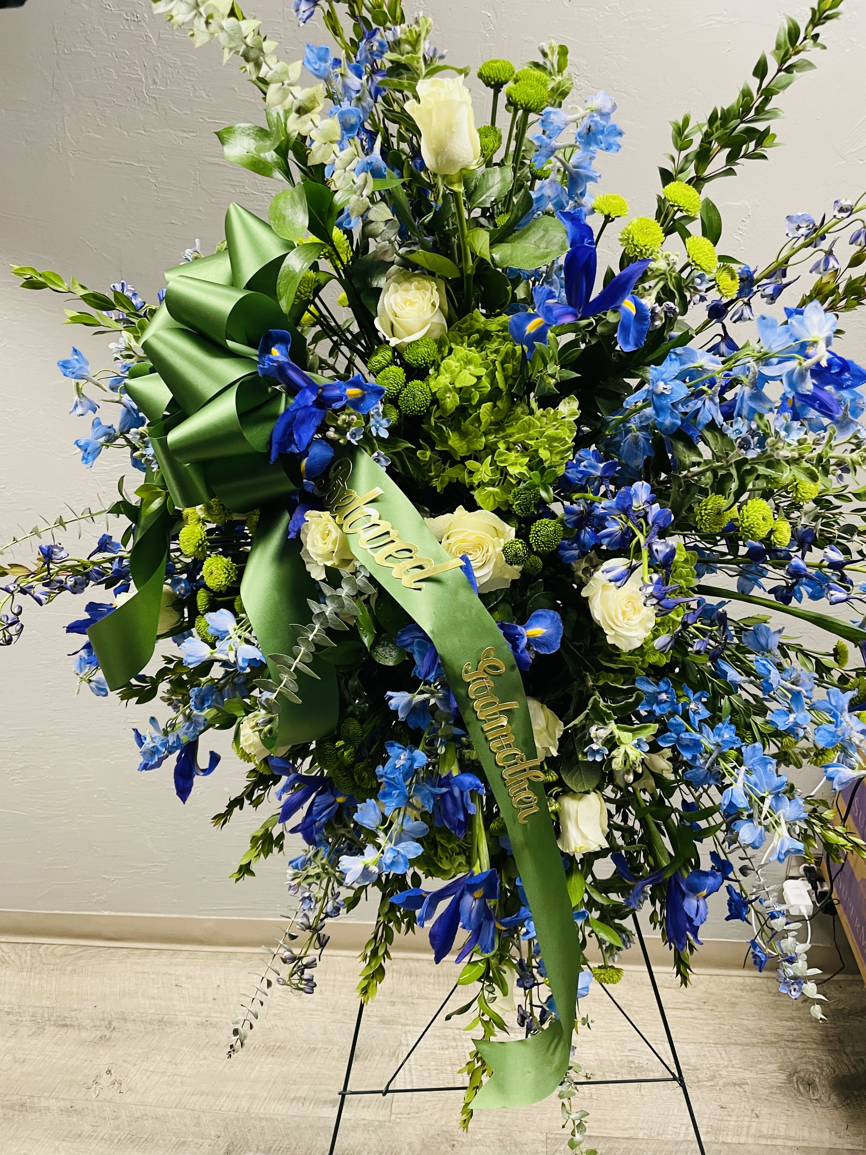 Large blue and white floral standing spray with green ribbon