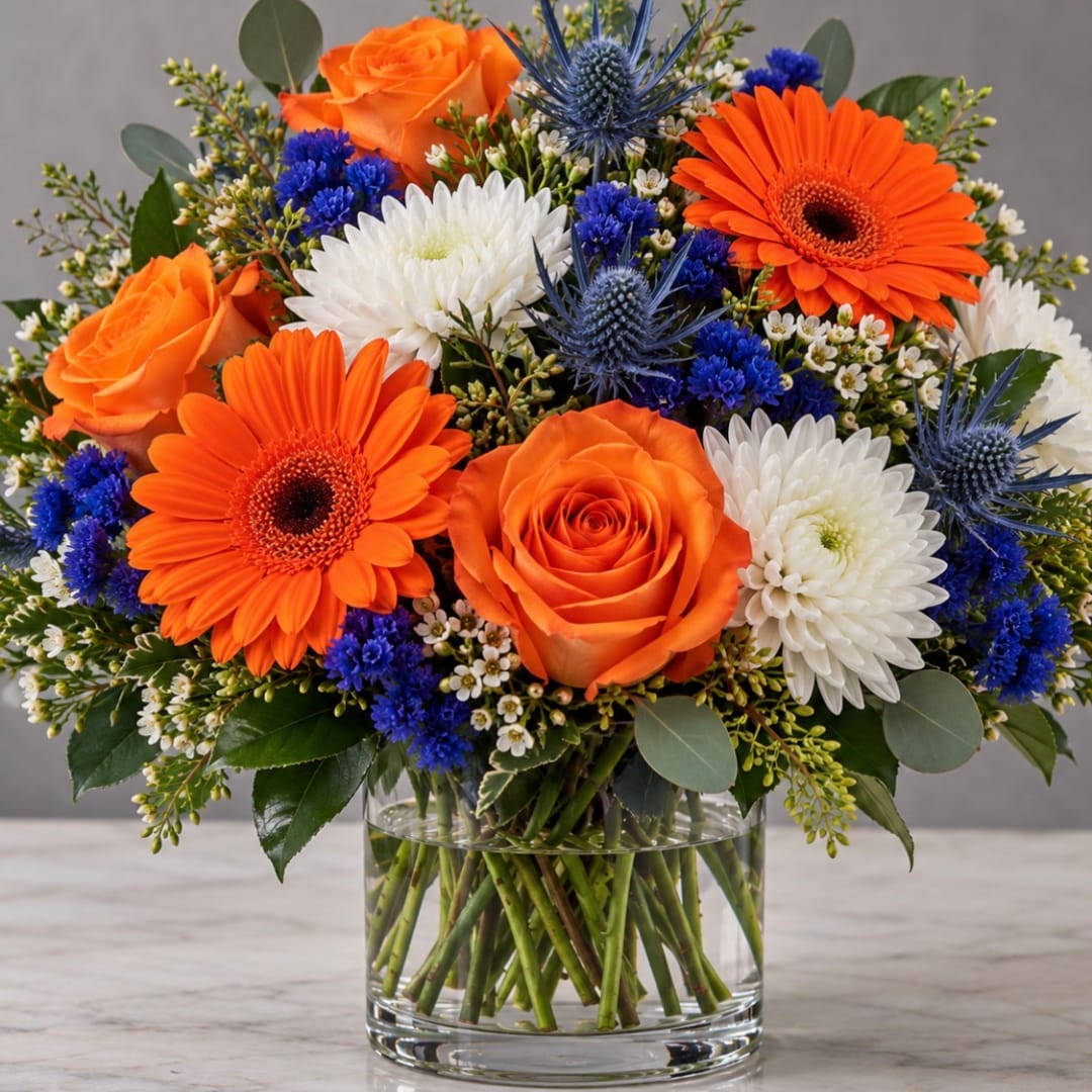 Orange roses and gerbera daisies in a clear glass vase