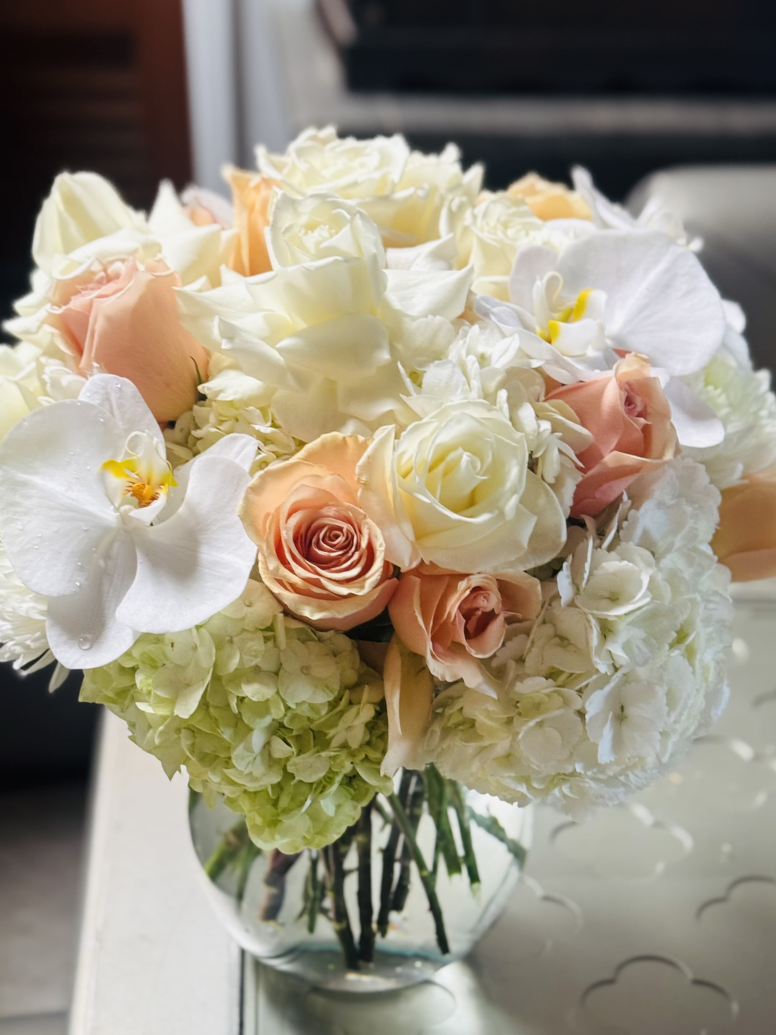 Bouquet of white and peach roses with white orchids in a glass vase