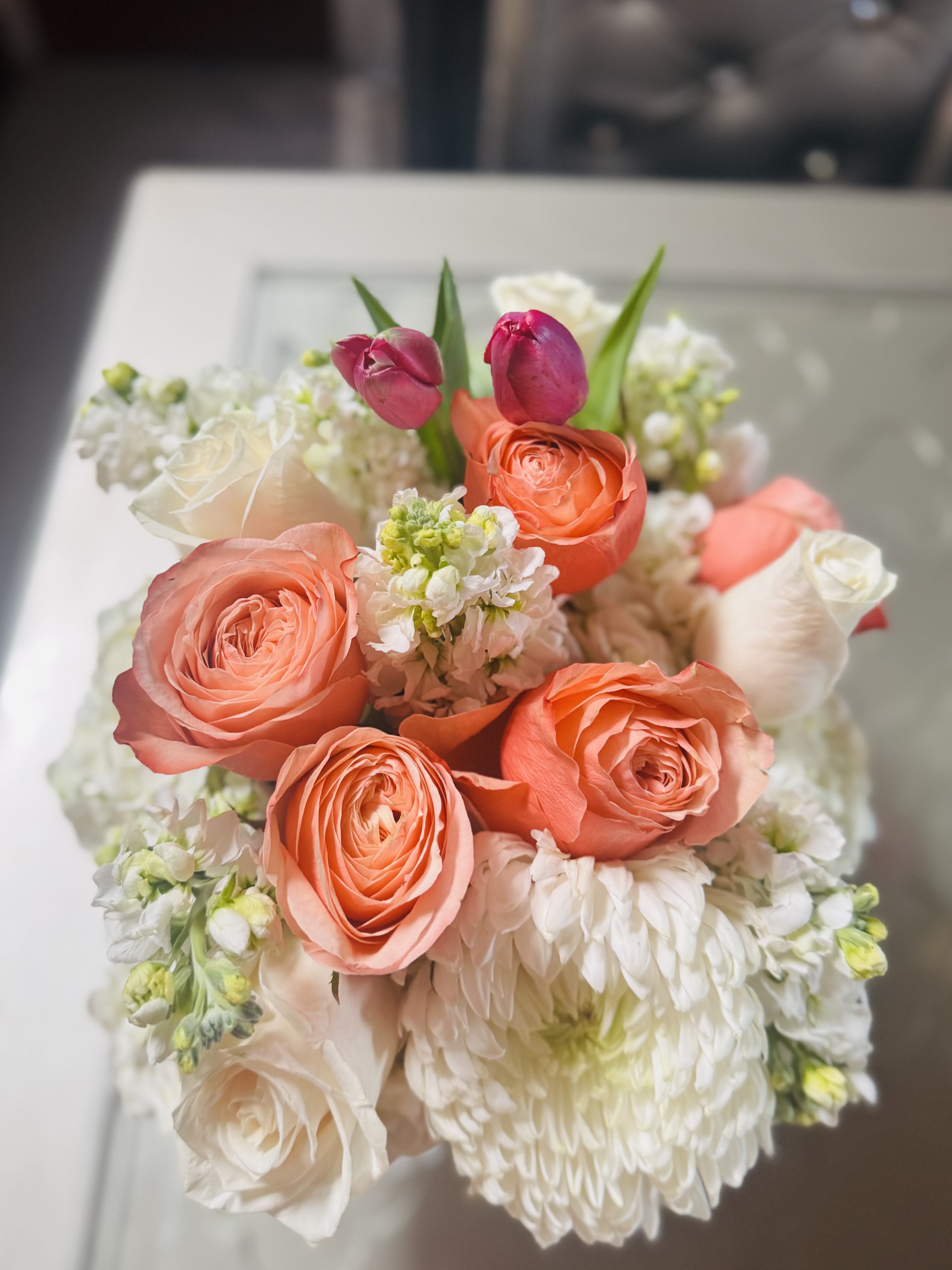 Bouquet of coral roses, white blooms, and pink tulips