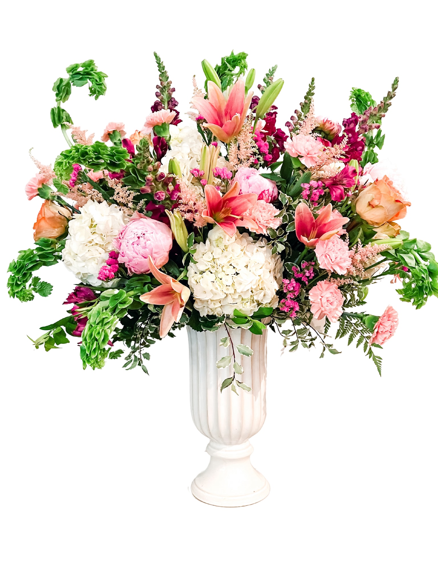 Large mixed flower arrangement in a white pedestal vase