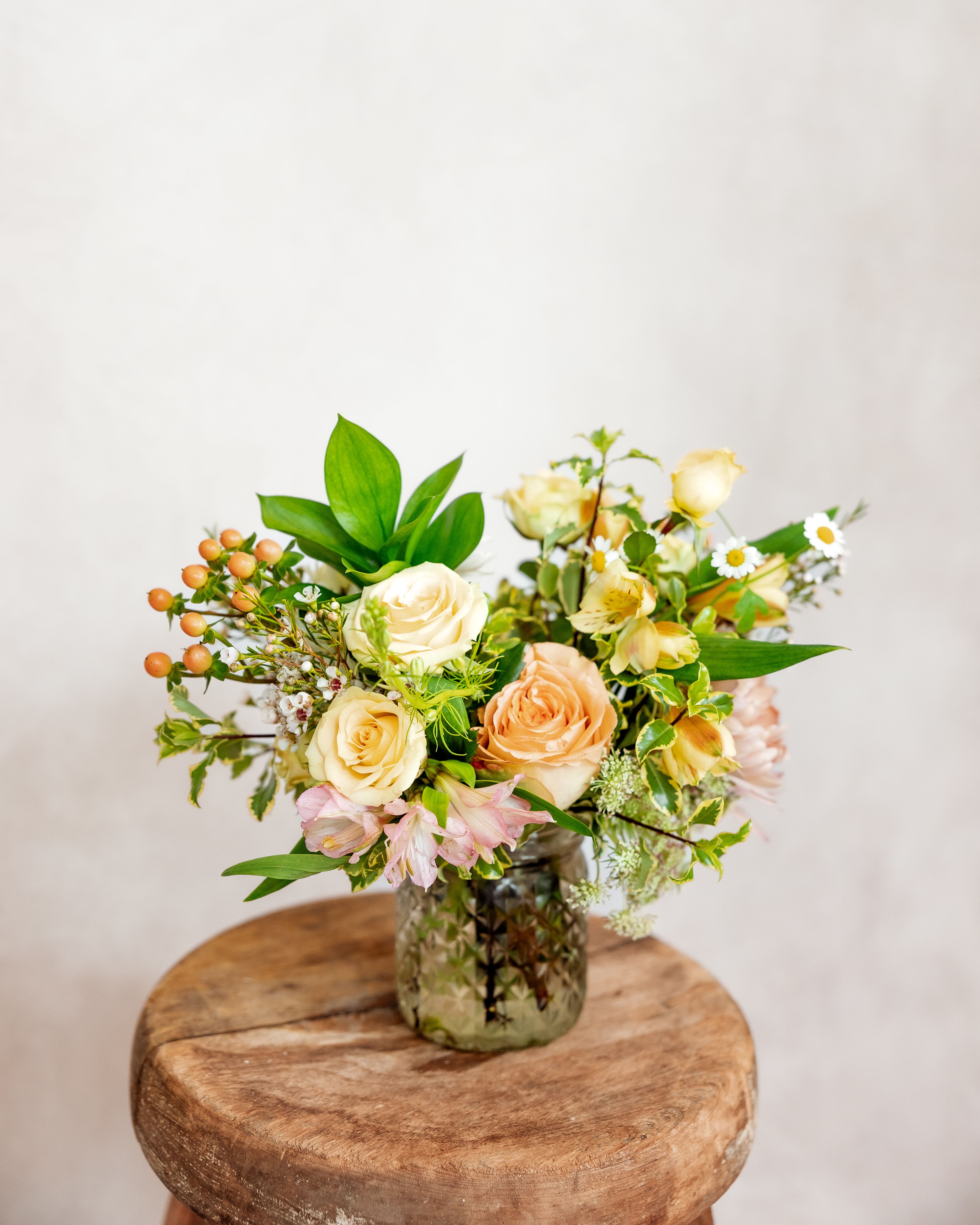 Cream and peach roses in a glass vase with small white flowers
