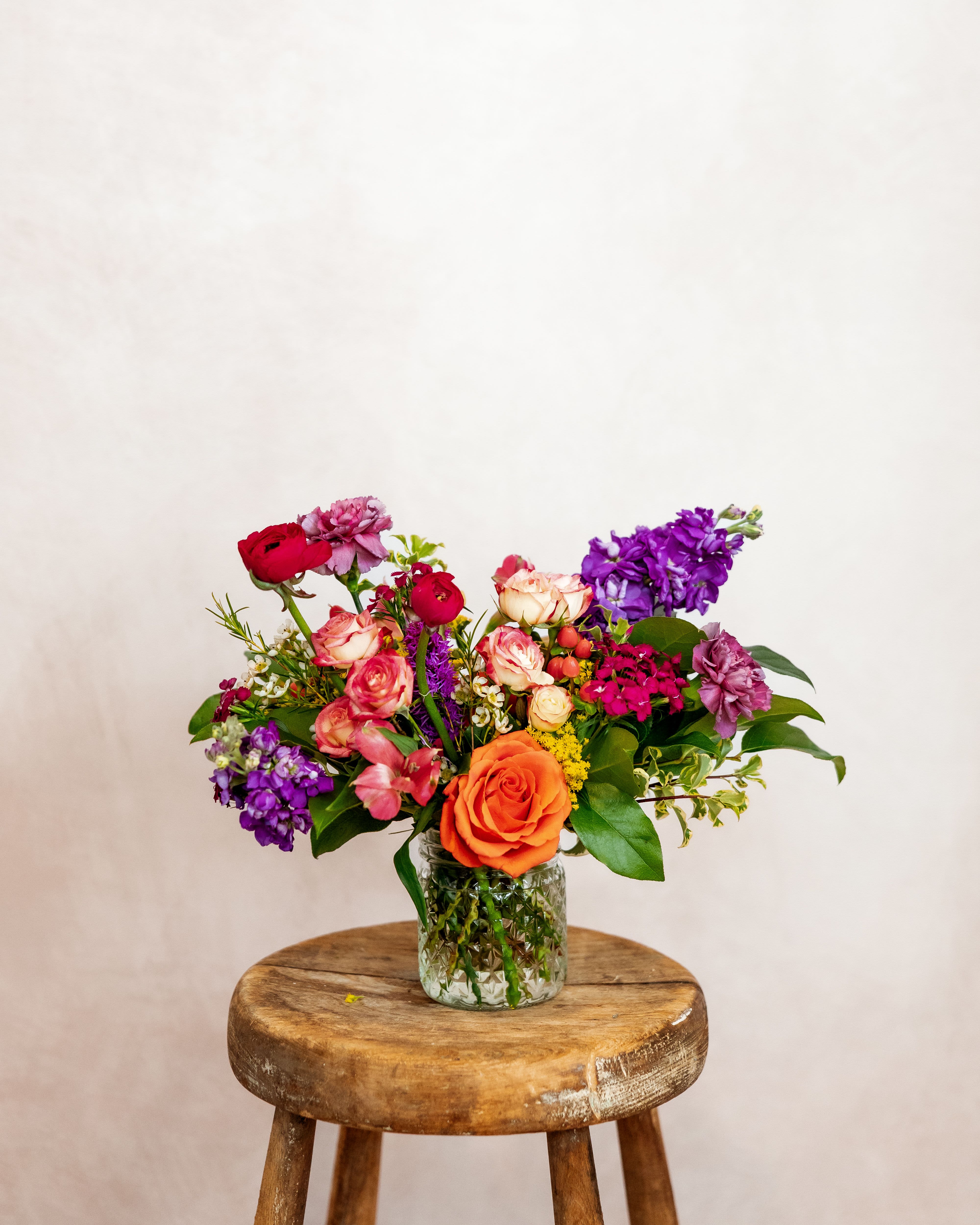 Mixed bouquet of roses and purple flowers in a glass vase