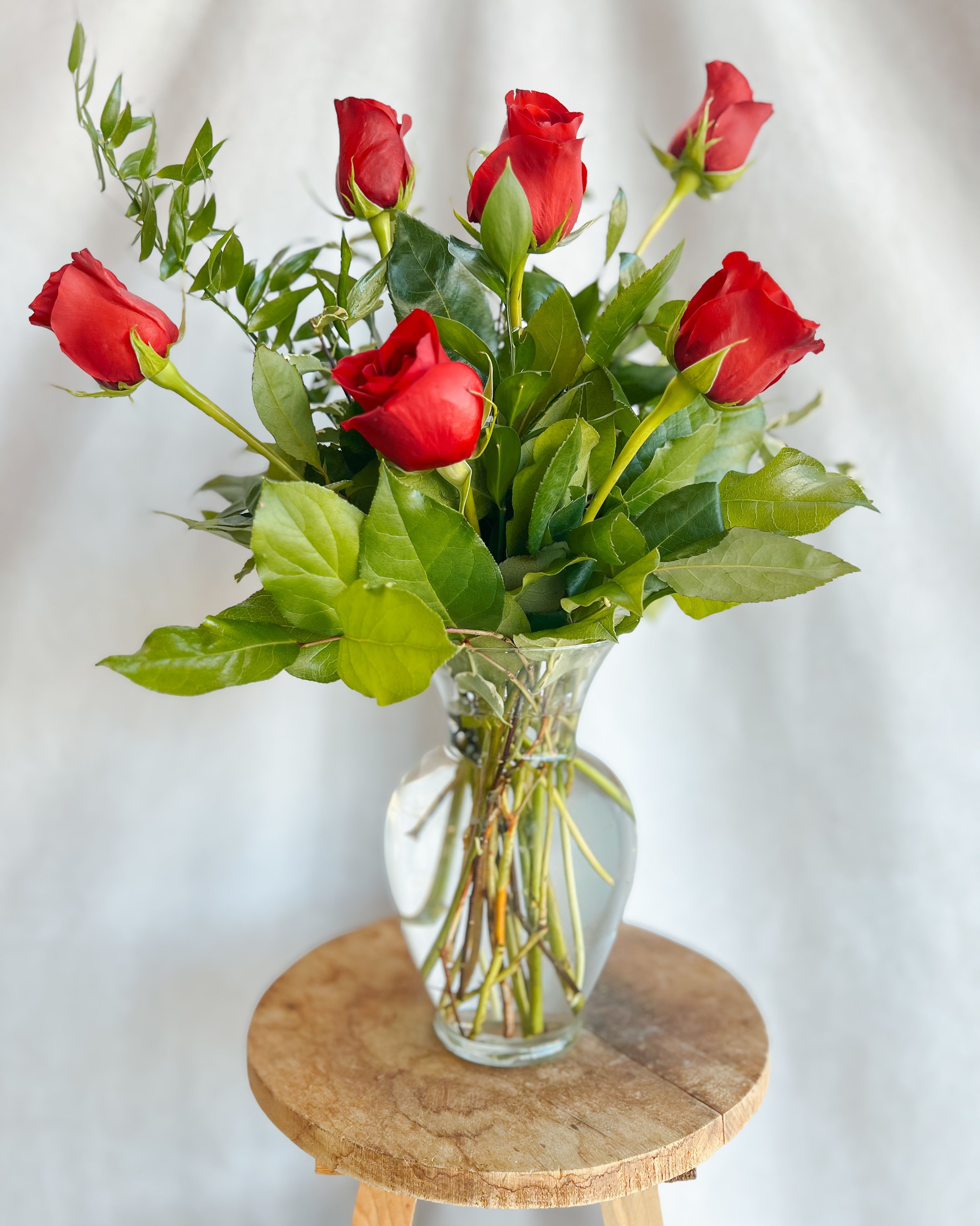 Red roses arranged in a clear glass vase