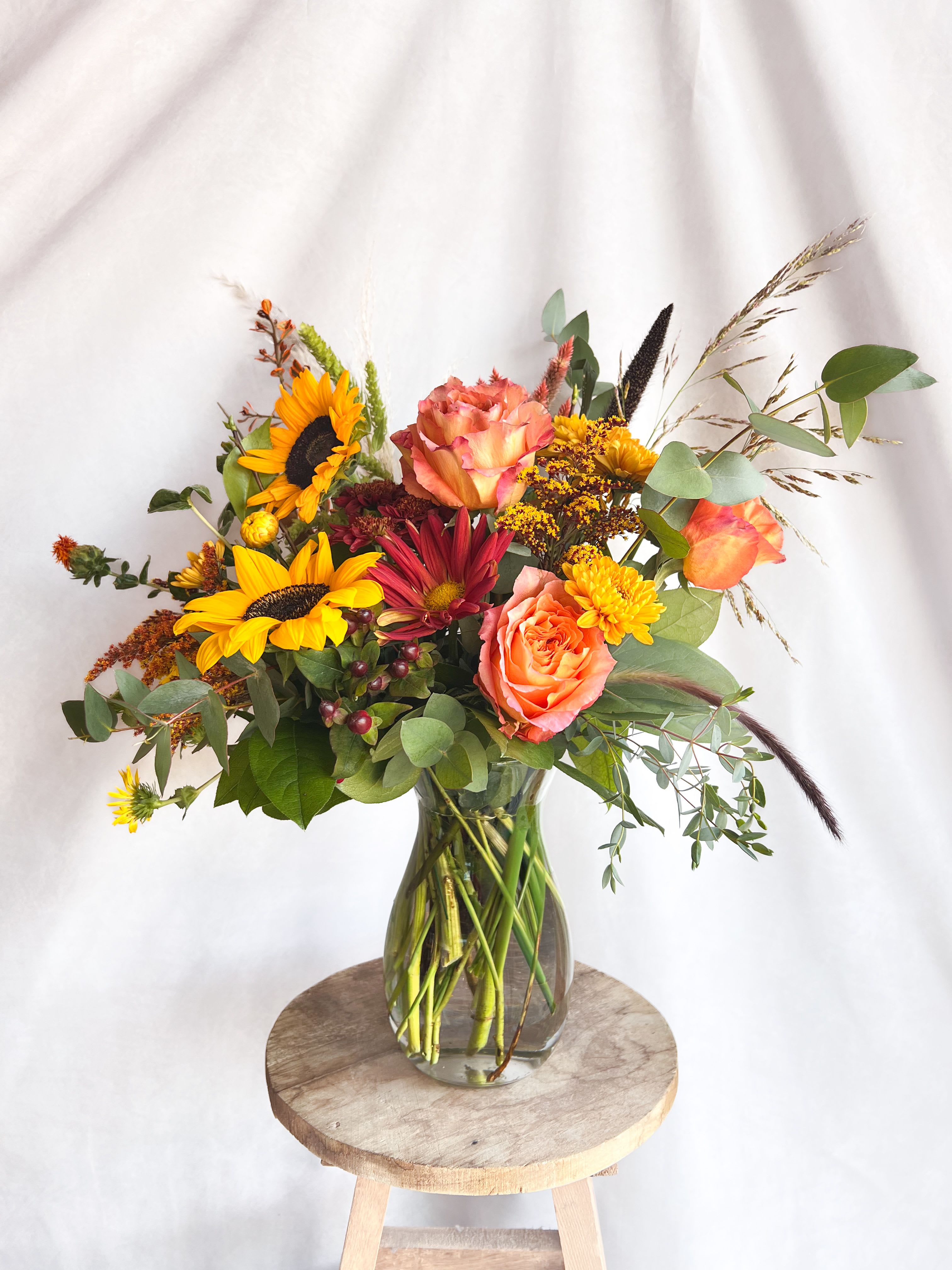 Mixed bouquet in a clear glass vase with sunflowers and peach roses