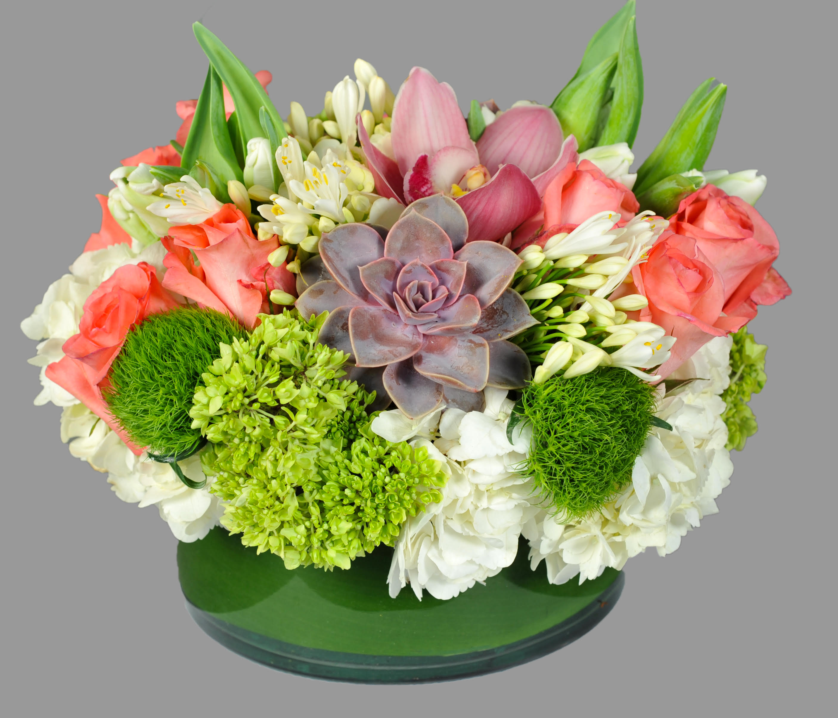 Mixed bouquet with pink roses, white blooms, and a central succulent in a green vase