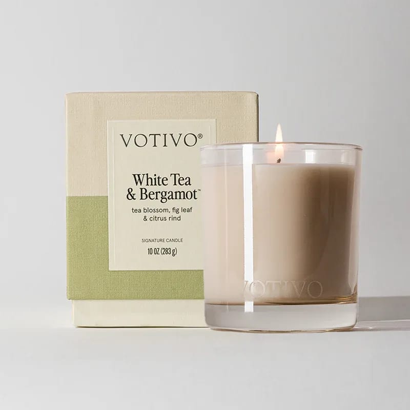 Lit white tea and bergamot candle beside its box