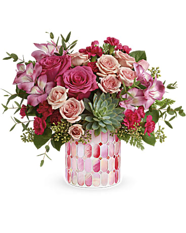 Pink and blush roses arranged in a patterned glass vase