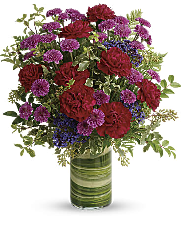 Red and purple flowers arranged in a glass vase