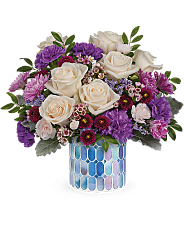 Blue Beauty Bouquet - Springtime beauty at its best! Creamy roses and deep purple blooms are oh-so-alluring in this shimmering, stained glass mosaic vase.  Crème roses, purple carnations, miniature light pink carnations, lavender cushion spray chrysanthemums, purple button spray chrysanthemums, pink waxflower and purple limonium are arranged with dusty miller and huckleberry. Delivered in Teleflora's Blue Beauty Mosaic vase. Approximately 13 3/4" W x 12 3/4" H