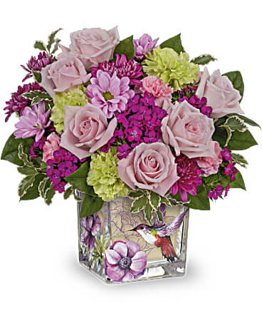 Pink roses and mixed blooms arranged in a square glass vase