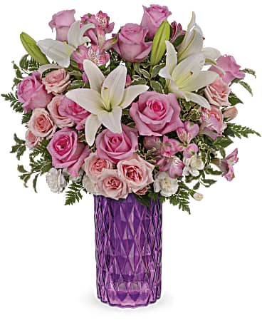 Pink roses and white lilies arranged in a purple vase