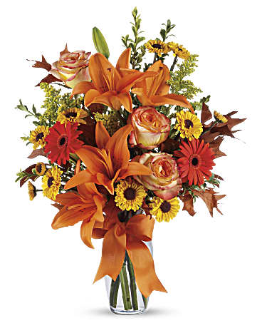Orange lilies and mixed flowers in a clear glass vase