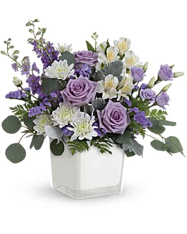 Lavender roses and white flowers in a clear square vase