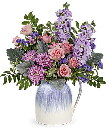 Pink and lavender flowers arranged in a ceramic pitcher vase