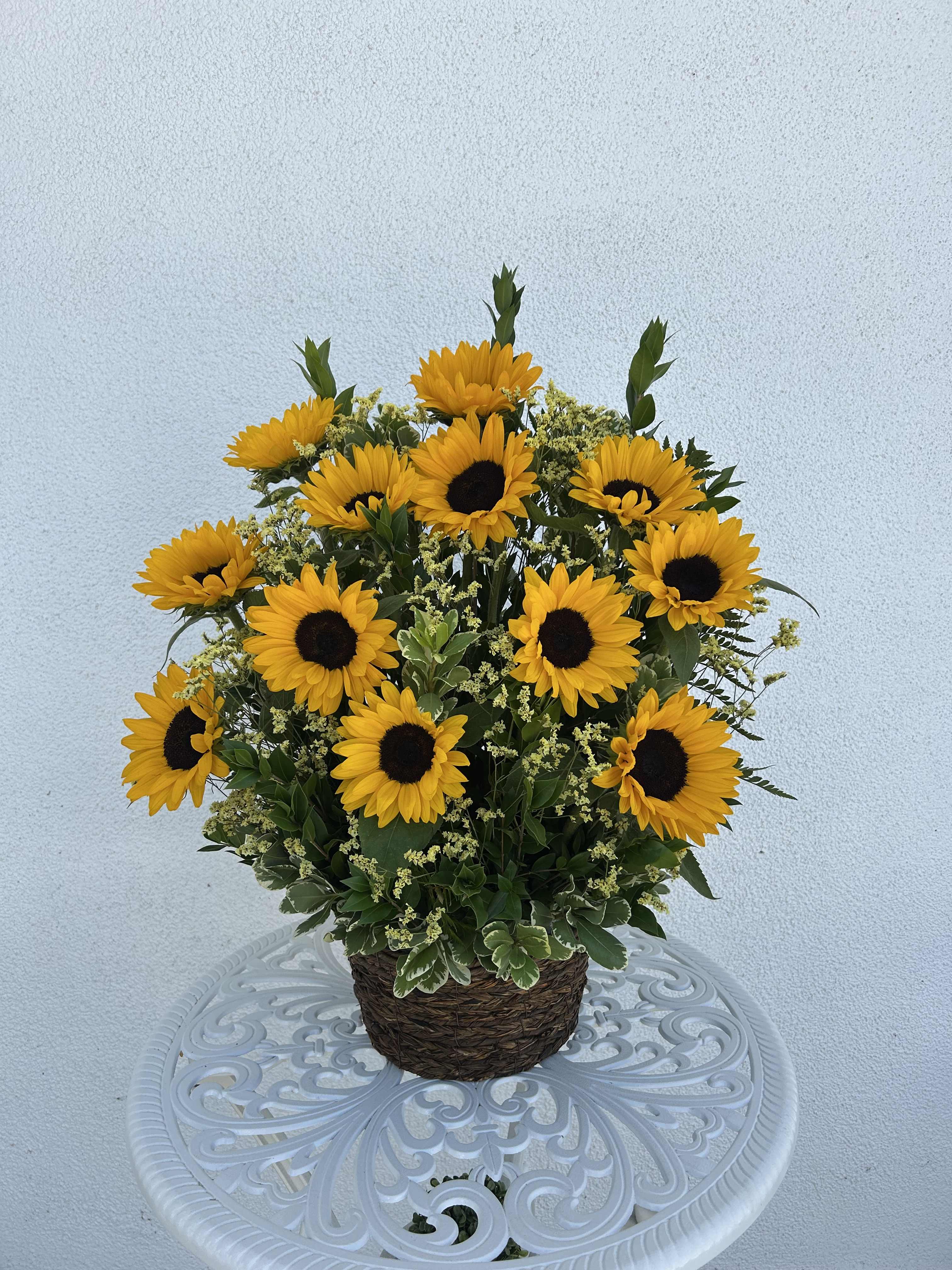 Potted arrangement of yellow sunflowers in a woven basket