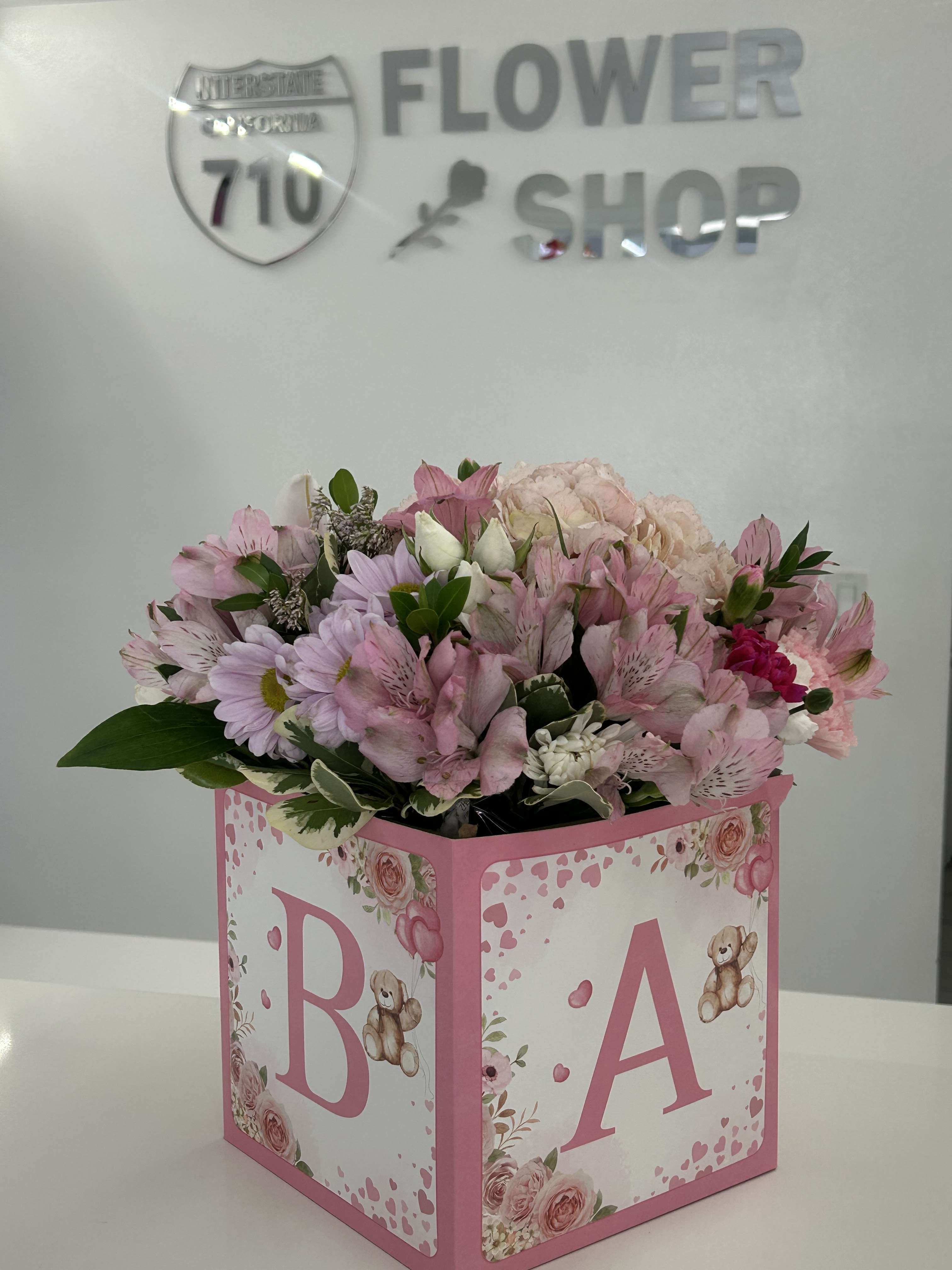 Pink and white bouquet in a decorated baby gift box with the letters B and A