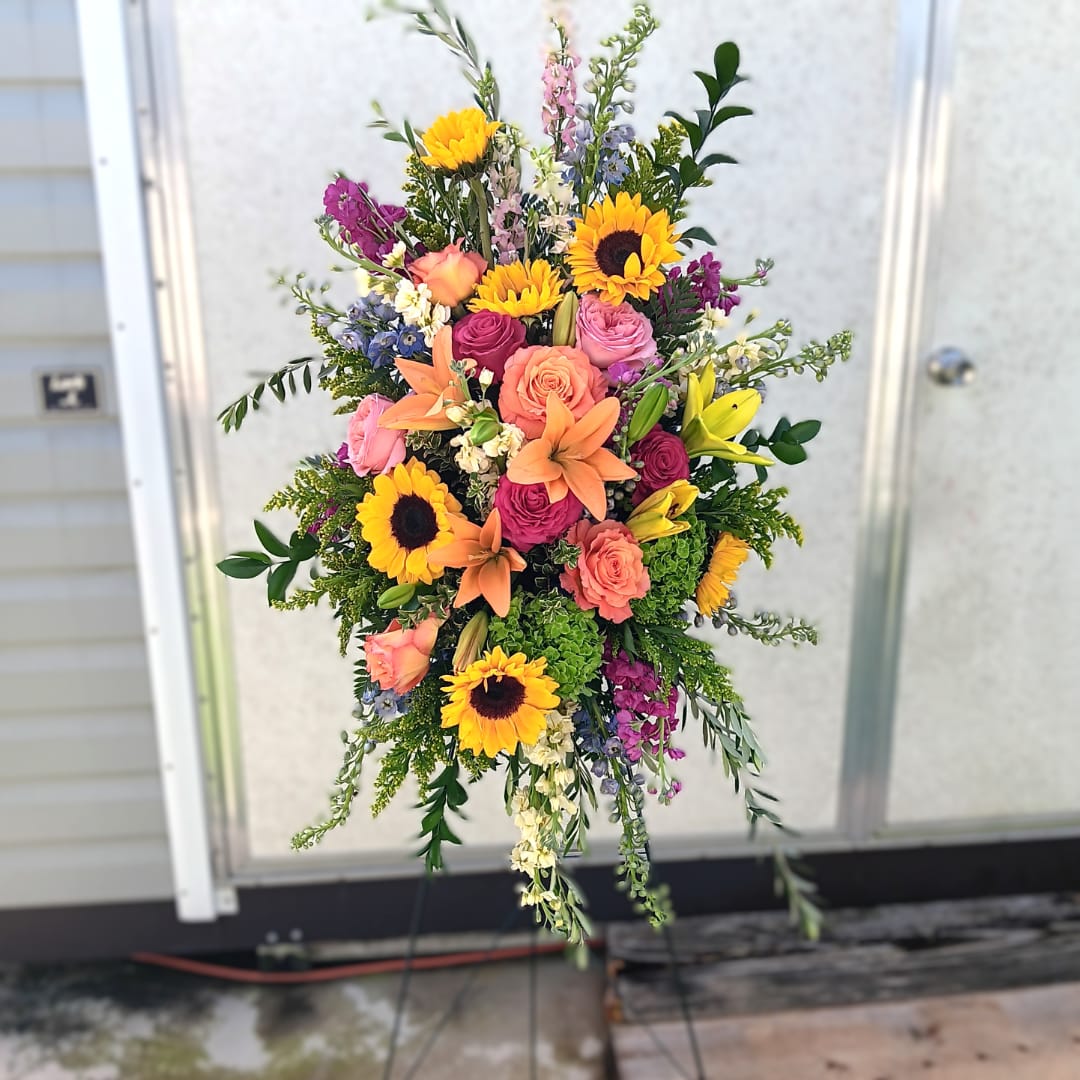 Tall mixed bouquet with sunflowers, roses, lilies, and purple accents