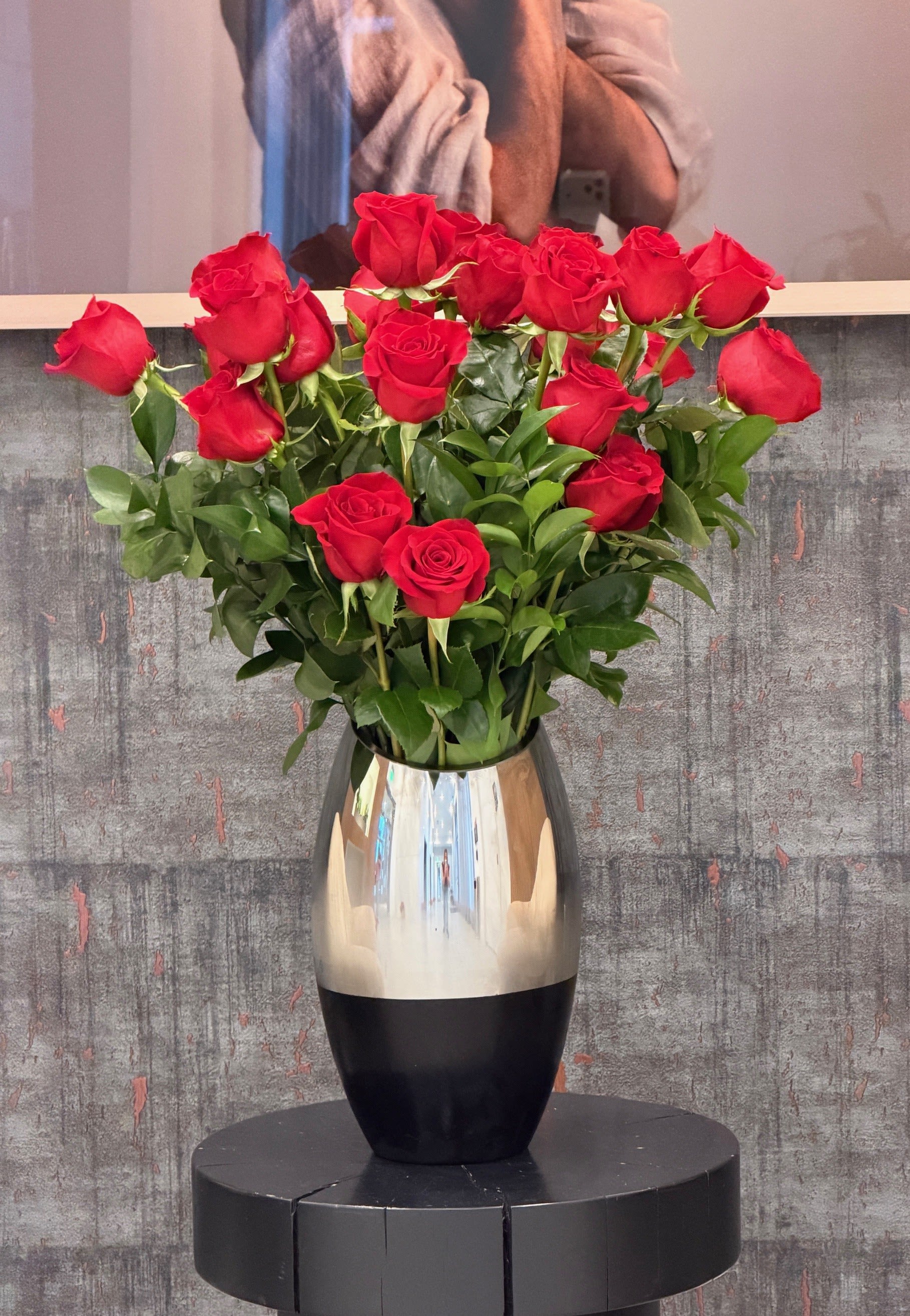 Red roses arranged in a reflective silver vase