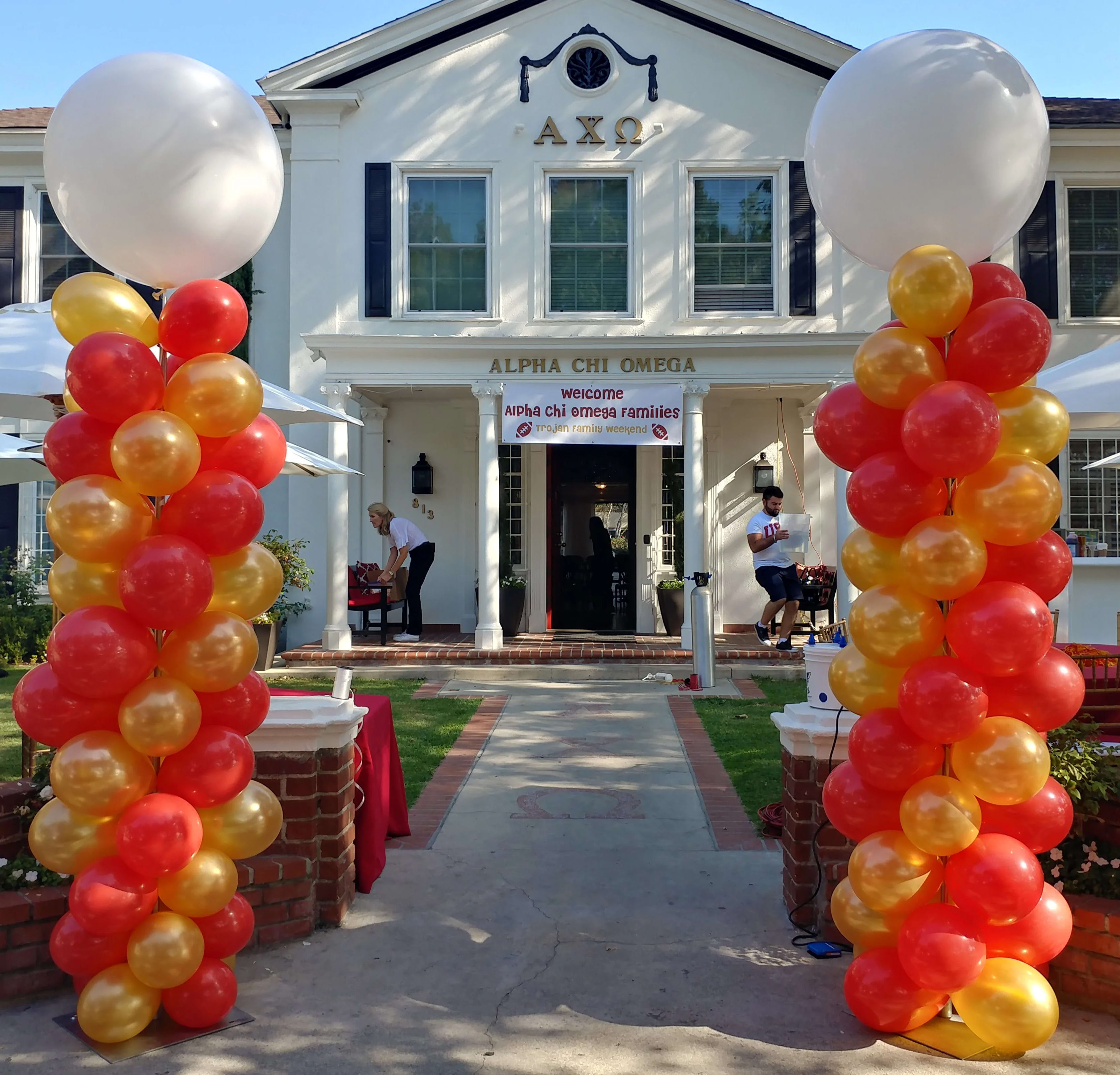 Red, orange, and gold balloon columns frame a house entrance