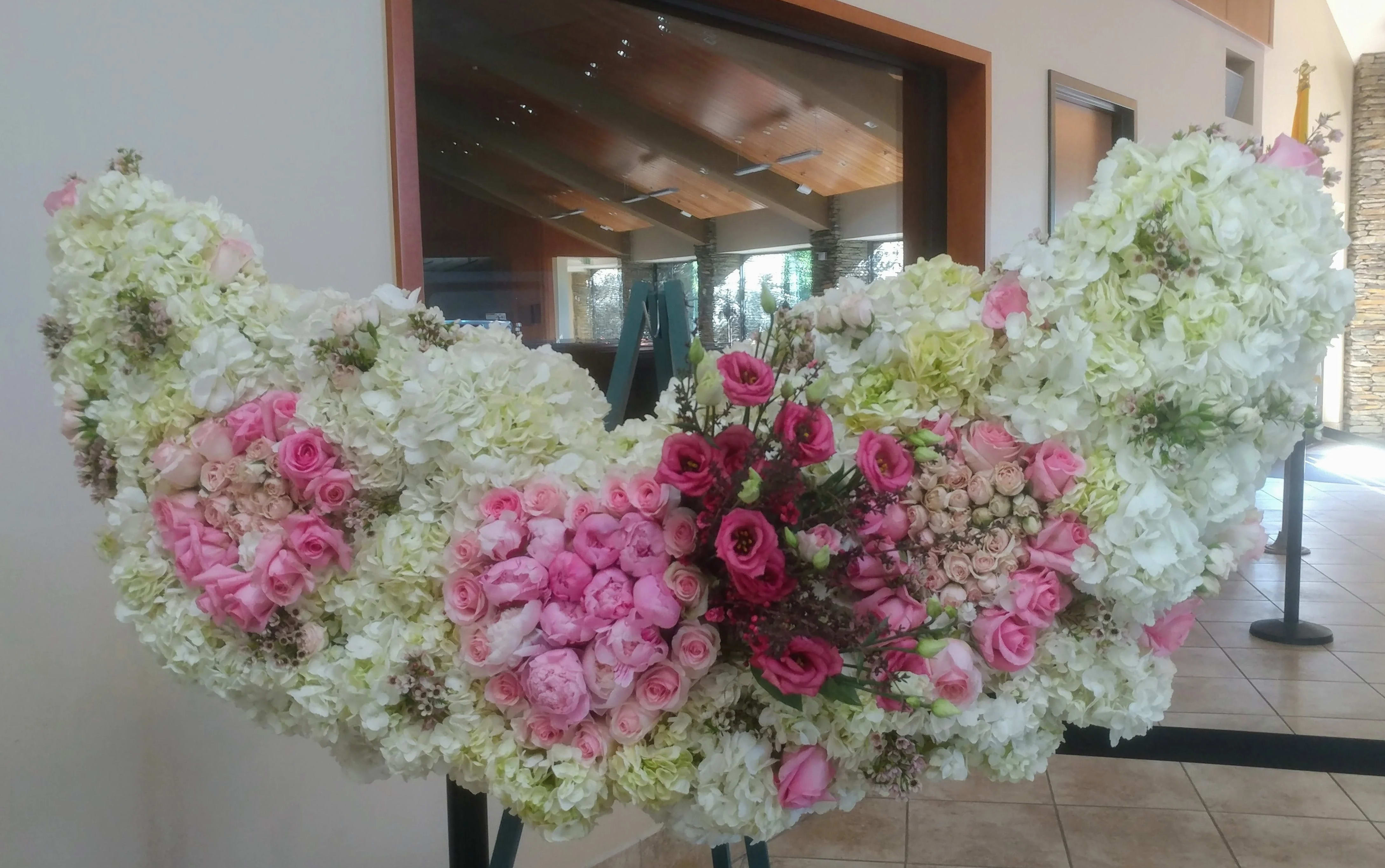 Large floral arrangement of white and pink flowers on a stand