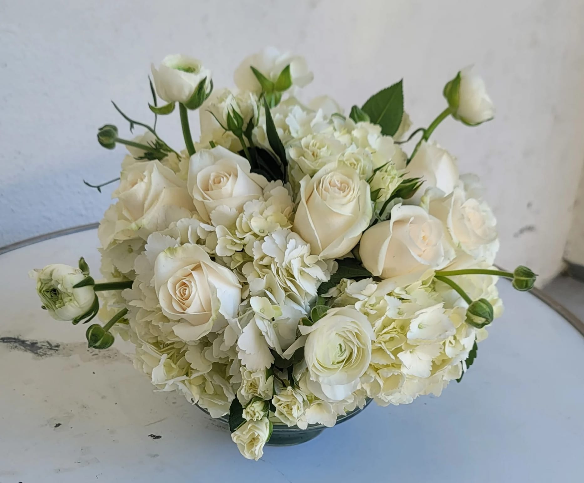 White roses and hydrangeas arranged in a low bowl vase