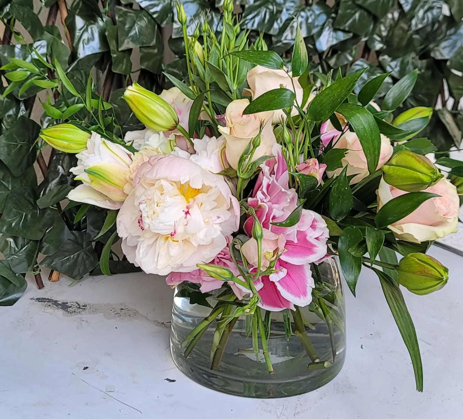 Pink and white flowers arranged in a clear glass vase