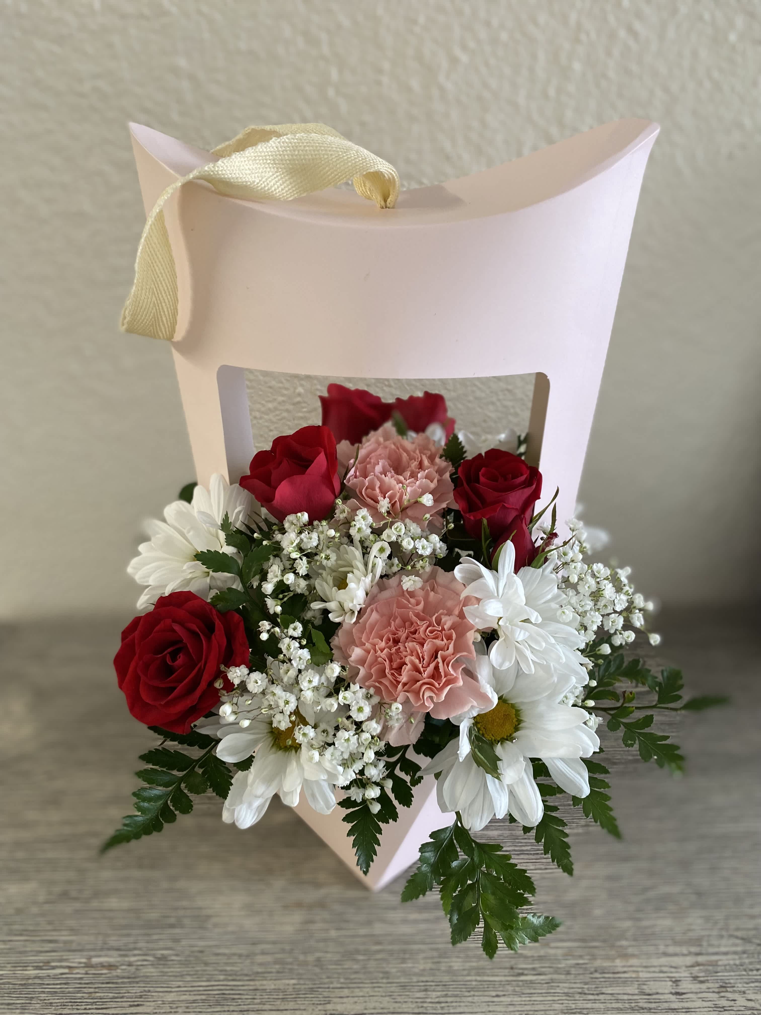 Pink gift box with red roses, pink carnations, and white daisies
