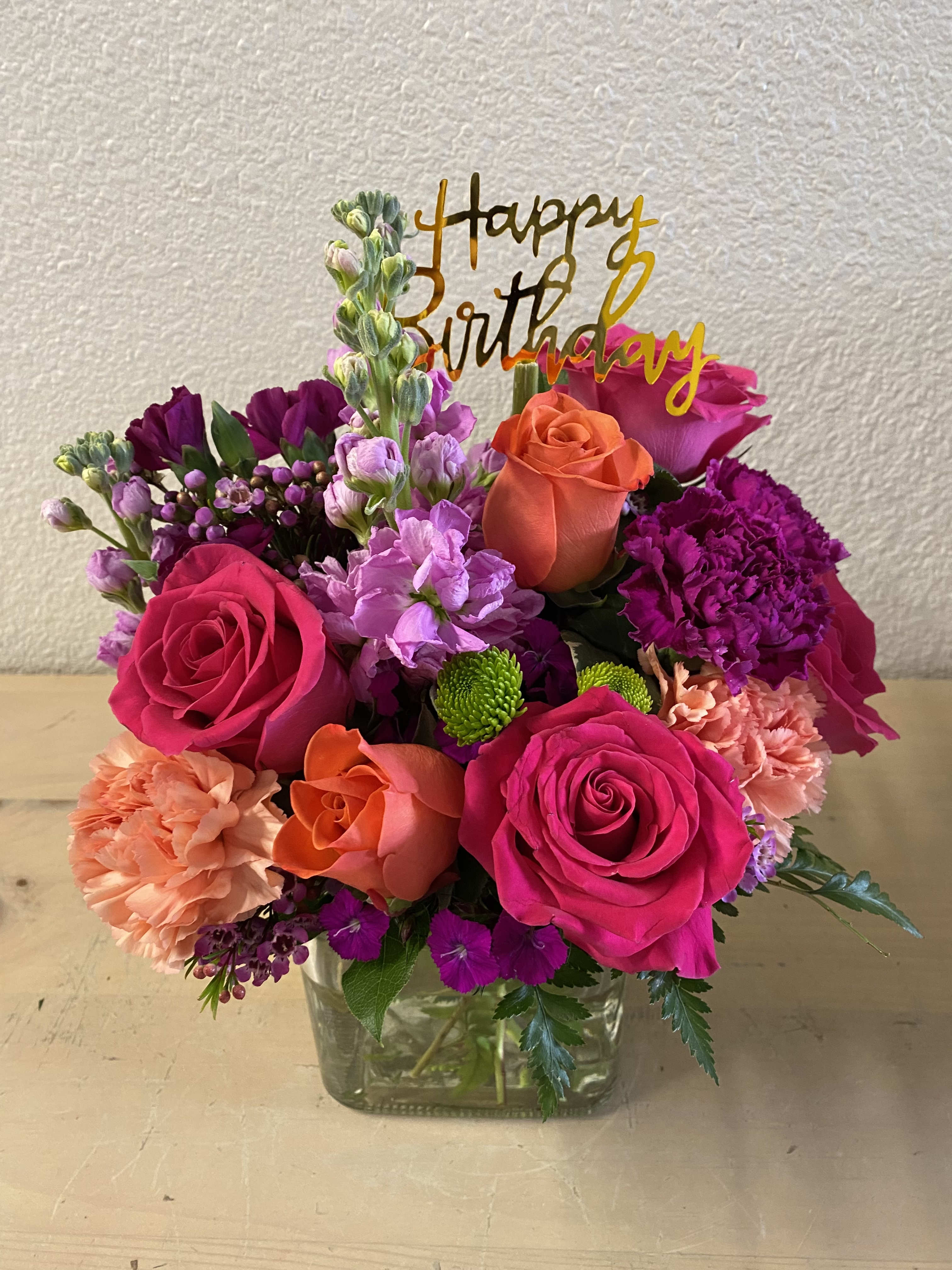 Bright mixed bouquet in a glass vase with a birthday topper