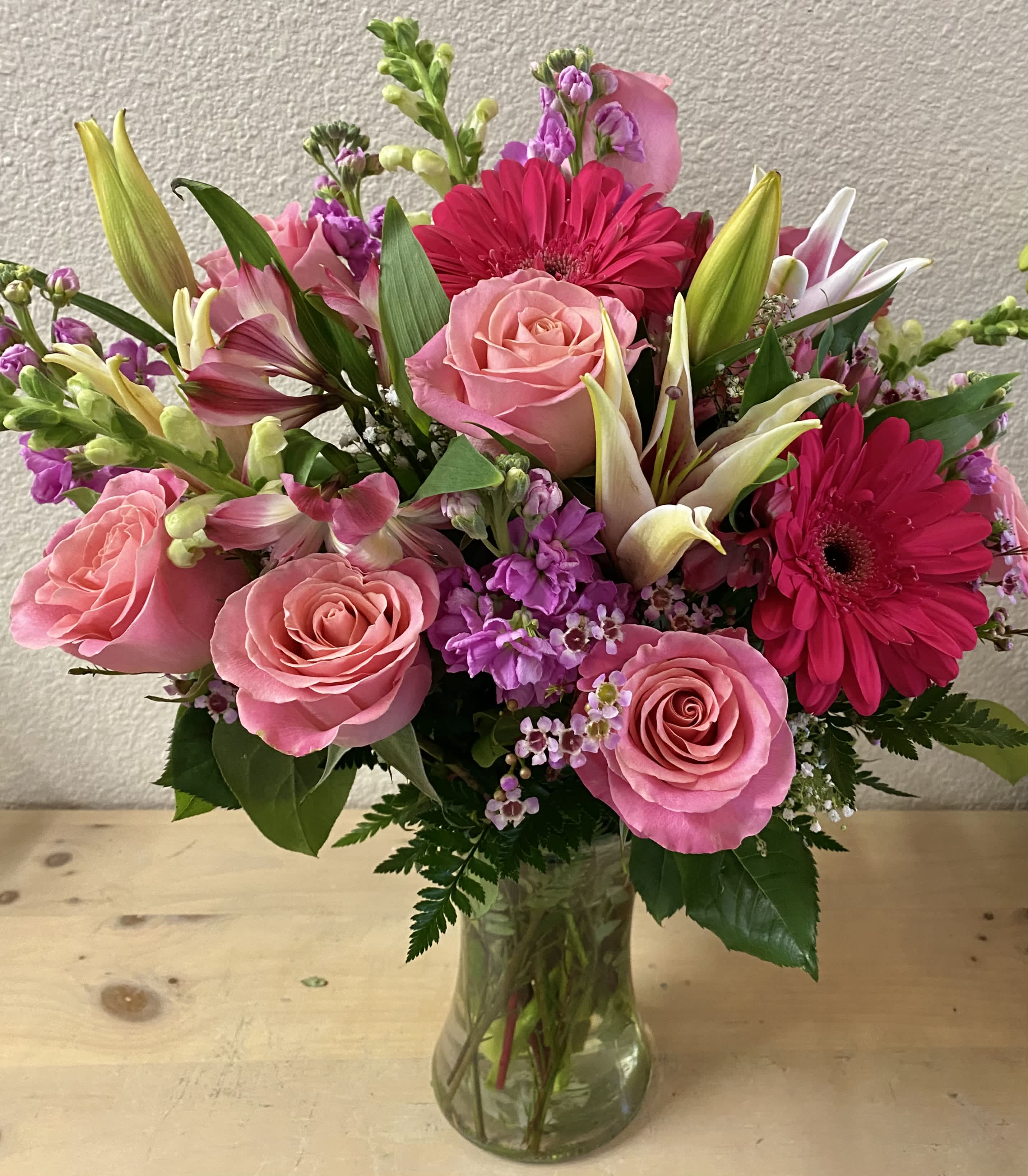 Pink roses and hot pink gerbera daisies in a clear glass vase